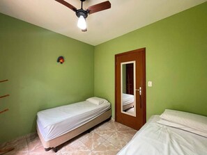 Una habitación con dos camas, un ventilador de techo y una puerta con espejo.