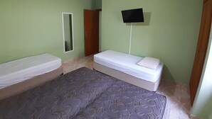 Ein Schlafzimmer mit zwei Betten, einem Deckenventilator, einem Flachbildfernseher und einem Spiegel.