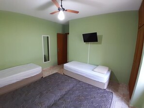 A bedroom with two beds, a ceiling fan, a flat-screen TV, and a mirror. - House with air conditioning 50m from Riviera Beach, house with Wi-Fi.  (Bertioga)