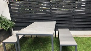 Eine Terrasse mit Tisch und zwei Bänken.