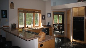 Eine Küche mit Granit-Arbeitsplatten, Holzschränken, einem schwarzen Kühlschrank und einem Essbereich mit Tisch und Stühlen.