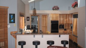 Eine Küche mit Holzausstattung, einer zentralen Kochinsel mit Barhocker, einer Mikrowelle und einem Kühlschrank.