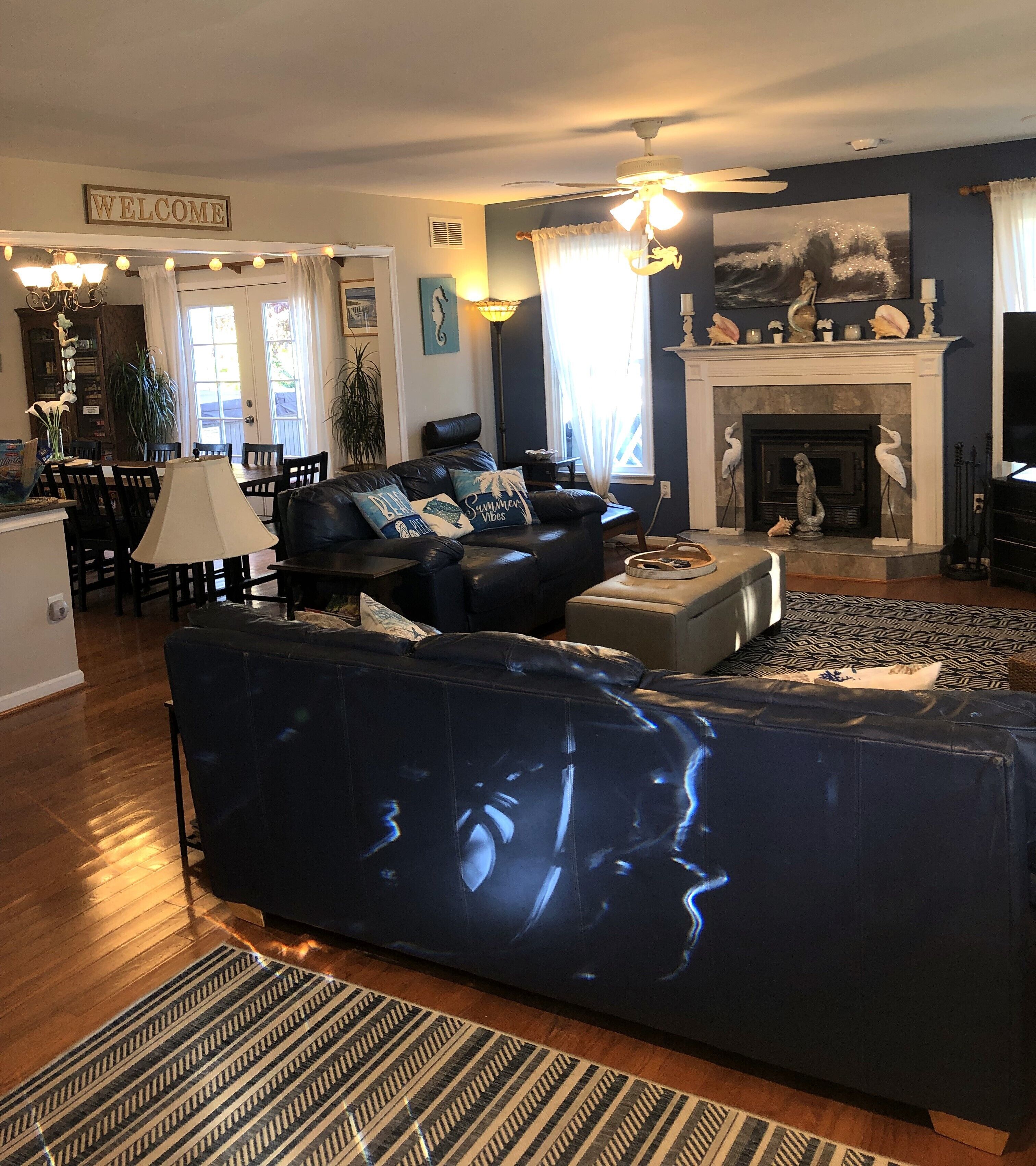 A living room with a dark blue sofa, a fireplace, and a dining area with a table and chairs.