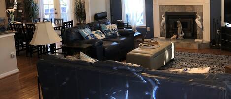 A living room with a dark blue sofa, a fireplace, and a dining area with a table and chairs.