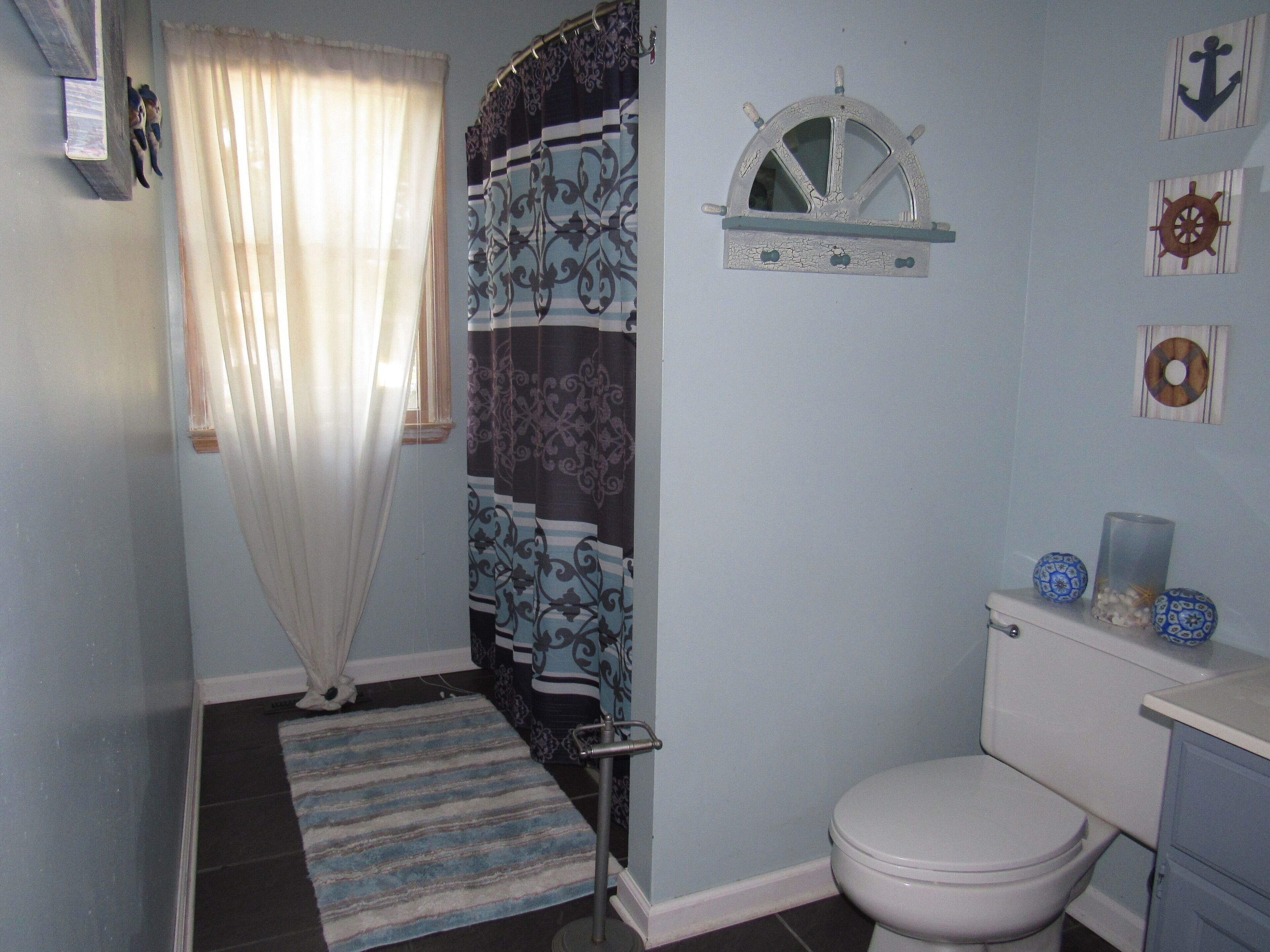 Ein Badezimmer mit Toilette, Waschbecken und einer Duschvorhang mit maritimen Motiven.