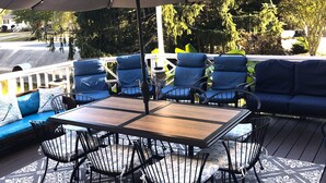 Une terrasse extérieure avec une table et des chaises, un grand parasol et un canapé.