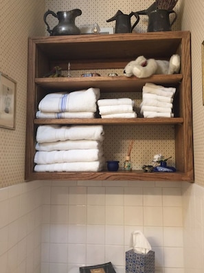 Ein Badezimmer mit einem Holzboden, der Handtücher, eine Dekoration und einen kleinen blauen Behälter beherbergt.