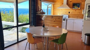 A modern kitchen with wooden walls, a round dining table, and a view of the sea. - Lake views, boating, skiing and hot pools (Omori)