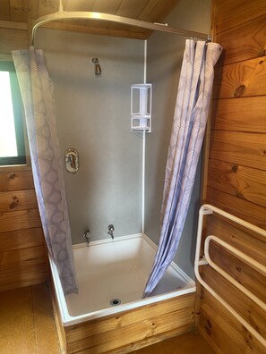 Un box de ducha con asiento integrado y cabezal de ducha de mano.