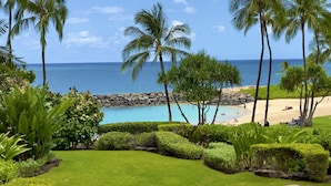 A tropical beach resort with a clear view of the ocean, palm trees, and a swimming pool. - Nalu Collection 2/2 Oceanfront Living~Luxurious Amenities (Kapolei)