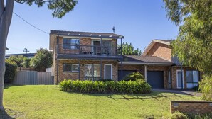 A two-story house with a balcony, a garage, and a well-maintained lawn. - Horizons in Mollymook (Mollymook Beach)