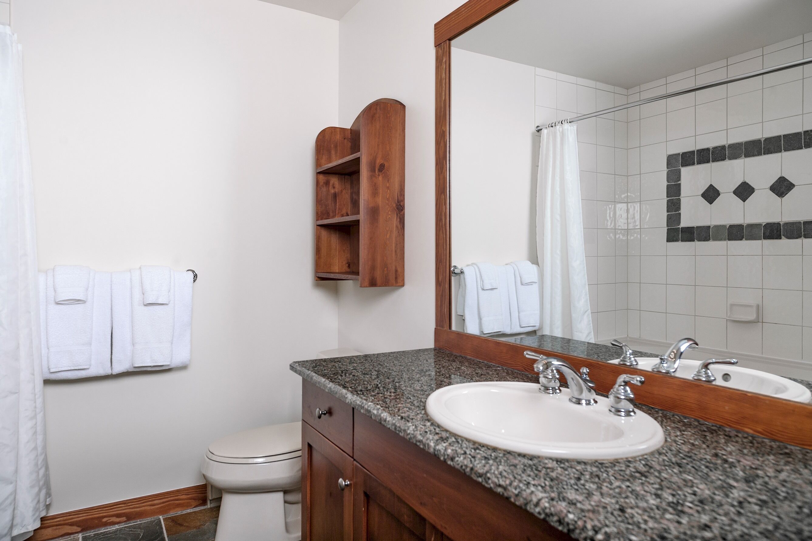 Une salle de bain avec un lavabo à vasque en granit, un meuble en bois et un grand miroir.
