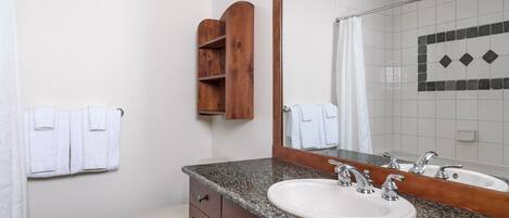 Une salle de bain avec un lavabo à vasque en granit, un meuble en bois et un grand miroir.
