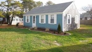 A single-story house with a gabled roof, a small front yard, and a wooden fence in the background.