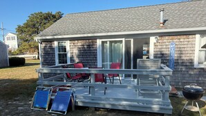 A deck with outdoor furniture, a grill, and a covered area with a sign.
