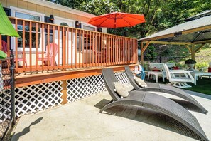 A covered outdoor deck with a wooden railing, lounge chairs, and a red umbrella. - Pool Open Until Oct 15th! ~ 1 Mi to Dollywood (Pigeon Forge)