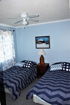 A bedroom with two beds, a ceiling fan, a nightstand with a lamp, and a framed picture on the wall. - Charming home on Montsweag Bay.  (Woolwich)