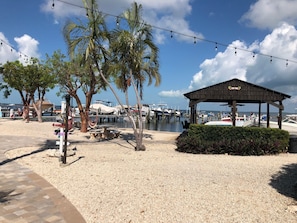 A beachside area with a gazebo, palm trees, and a marina in the background. - Beautiful Condo - Moon Bay - Waterfront - Spectacular Views in Key Largo (Key Largo)