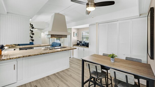 Une cuisine moderne avec des meubles blancs, un comptoir en granit et un ventilateur de plafond.
