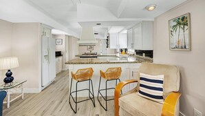 Une cuisine moderne avec des meubles blancs, un îlot central et des tabourets de bar.