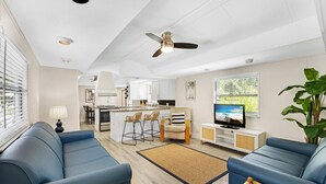 Un salon moderne avec un canapé, un téléviseur et une grande plante.