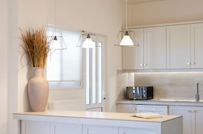 A modern kitchen with white cabinets, a microwave, and two pendant lights.