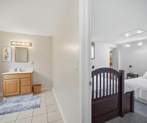 A bedroom with a bed, a dresser, a mirror, and a door leading to another room. - 33 W. Washington - Large Village Home with Room for the Whole Family! (Ellicottville)