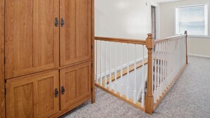 A room with a wooden wardrobe, a white railing, and a carpeted floor.