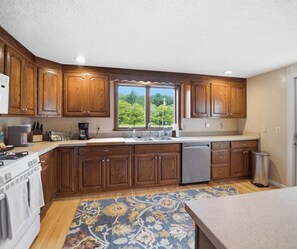 A kitchen with wooden cabinets, a stove, a sink, and a dishwasher. - 33 W. Washington - Large Village Home with Room for the Whole Family! (Ellicottville)