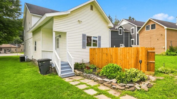 A residential property with a front yard, a wooden fence, and a stone pathway.