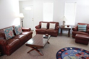 A living room with a brown leather sofa, a wooden coffee table, and a patterned rug.