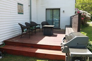 Eine Terrasse mit Gartenmöbeln, einem Grill und einer Schiebetür.