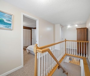 A staircase with wooden railings and carpeted steps leading to a bedroom with a bed and a closet. - 33 W. Washington - Large Village Home with Room for the Whole Family! (Ellicottville)