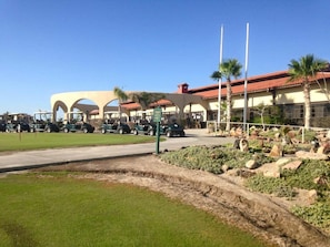 Un parcours de golf doté d’un club-house, de chariots de golf stationnés et de palmiers.