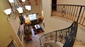 A multi-level interior with a staircase, a chandelier, a sofa set, and a dining area. - Condo 57-4 El Dorado Ranch (San Felipe)