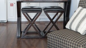 Eine moderne Küche mit weißen Schränken, einer zentralen Kochinsel mit Hockern, einer Mikrowelle und einem Toaster. An der Tür befindet sich ein Feuerschutzschild, und auf dem Boden liegt ein gemustertes Teppich.