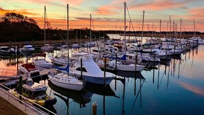 Ein Yachthafen mit verschiedenen Booten, die im ruhigen Wasser bei Sonnenuntergang liegen.