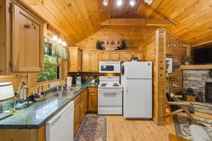 A wooden cabin interior with a kitchen featuring a stove, microwave, and refrigerator. - Follow Me to Tennessee! Book now! Plan your Spring getaway! Choice dates remain! (Gatlinburg)