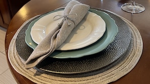 A dining table set with plates, a folded napkin, and a glass of water.