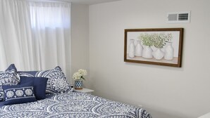 A bedroom with a large bed, a nightstand, a vase with flowers, and a framed picture on the wall. - Next Door To Lambeau Field /Sleeps 10+ (Green Bay)