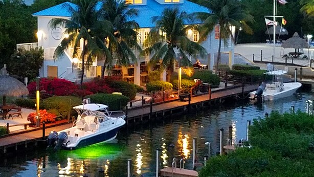 A waterfront property with a dock, a boat, and a building with a blue roof. - Ocean Front Private Beach, Pool/Hot Tub, Pool Bar, Marina with Cafe (Tavernier)
