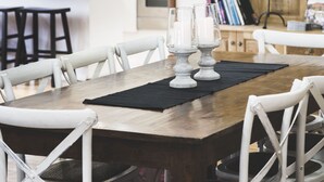 A dining area with a wooden table, white chairs, and a black placemat. There are two black pendant lights above the table. - Eurunderee House - nestled in Mudgee’s famous vineyards (Eurunderee)