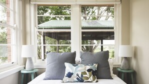 A bedroom with a bed, two nightstands, two lamps, and a window with a view of trees and a building. - Eurunderee House - nestled in Mudgee’s famous vineyards (Eurunderee)
