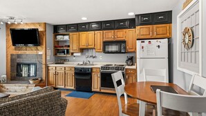 A modern kitchen with wooden cabinets, a built-in oven, microwave, and refrigerator. - 'Escape Plan'  great location for year round fun (Mancelona)