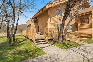 A wooden cabin with a balcony, a deck, and a fenced yard.