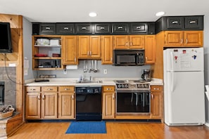 A kitchen with wooden cabinets, a microwave, a refrigerator, a dishwasher, and a stove. - 'Escape Plan' great location for year round fun (Mancelona)
