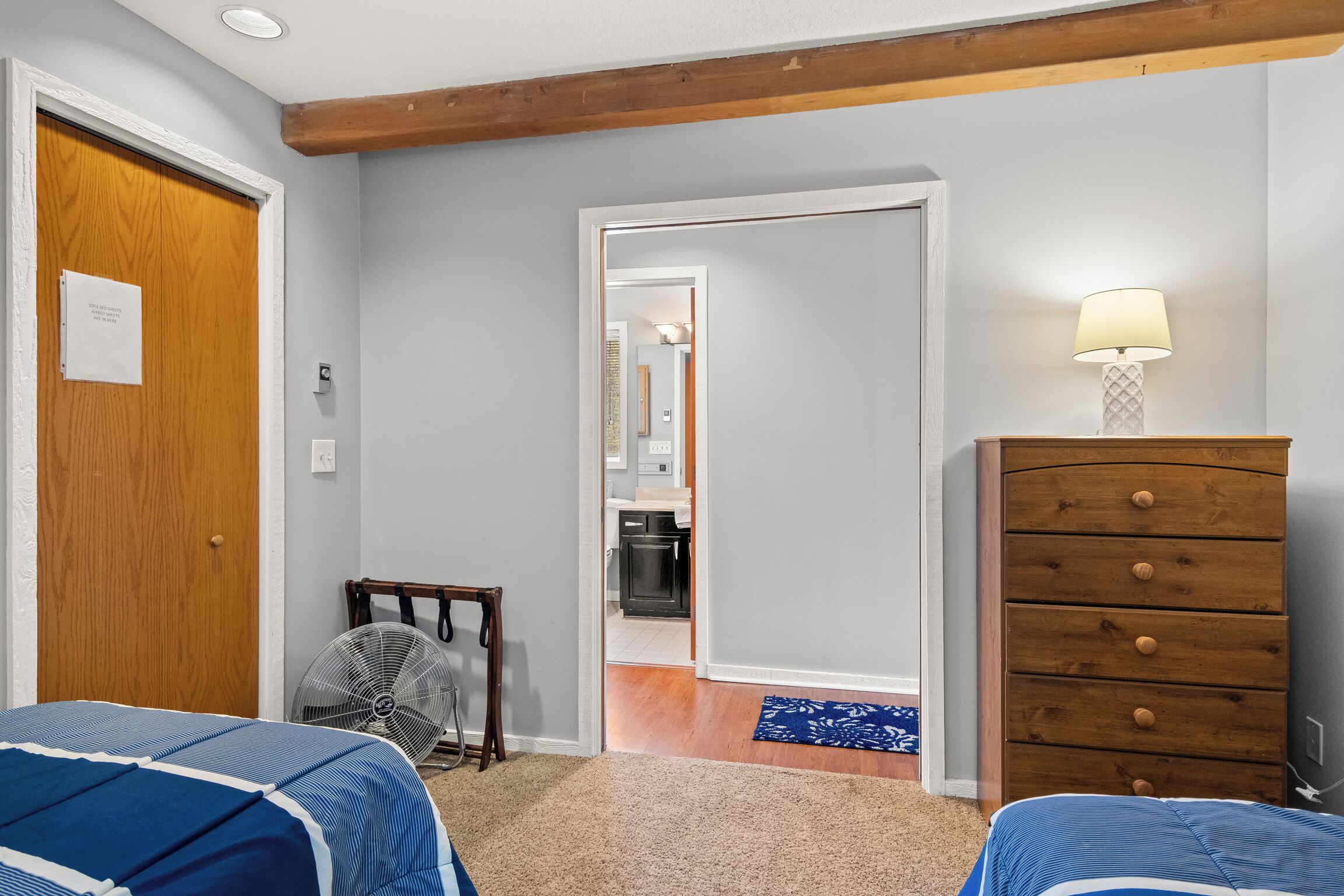 Een slaapkamer met een houten deur, een dressoir, een ventilator en een lamp.