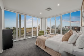 Enjoy expansive city views from the large bed against floor-to-ceiling windows.