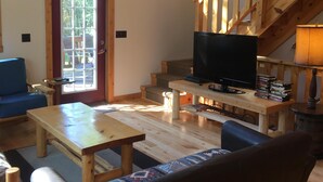 Un accogliente soggiorno con una scala in legno, una testa di cervo appesa al muro, una televisione e una libreria.