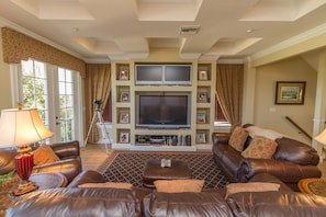 A living room with a large flat-screen TV, leather sofas, a coffee table, and a patterned rug. - Reunion Disney Villa, Luxury Villa in a gated community, minutes away from WDW. (Reunion)